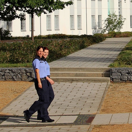 Zwei Polizistinnen laufen in Uniform über ein Gelände.